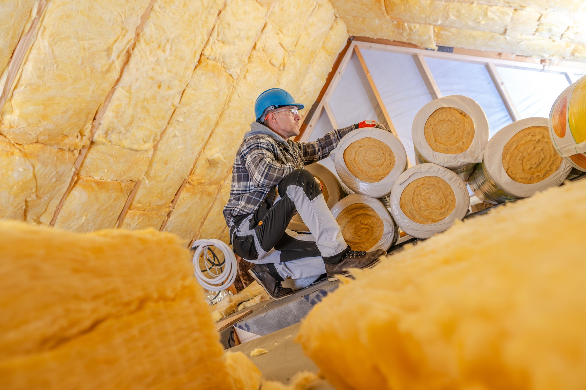 Worker Installing Mineral Wool Insulation in a Residential Attic During Daytime Renovation Process