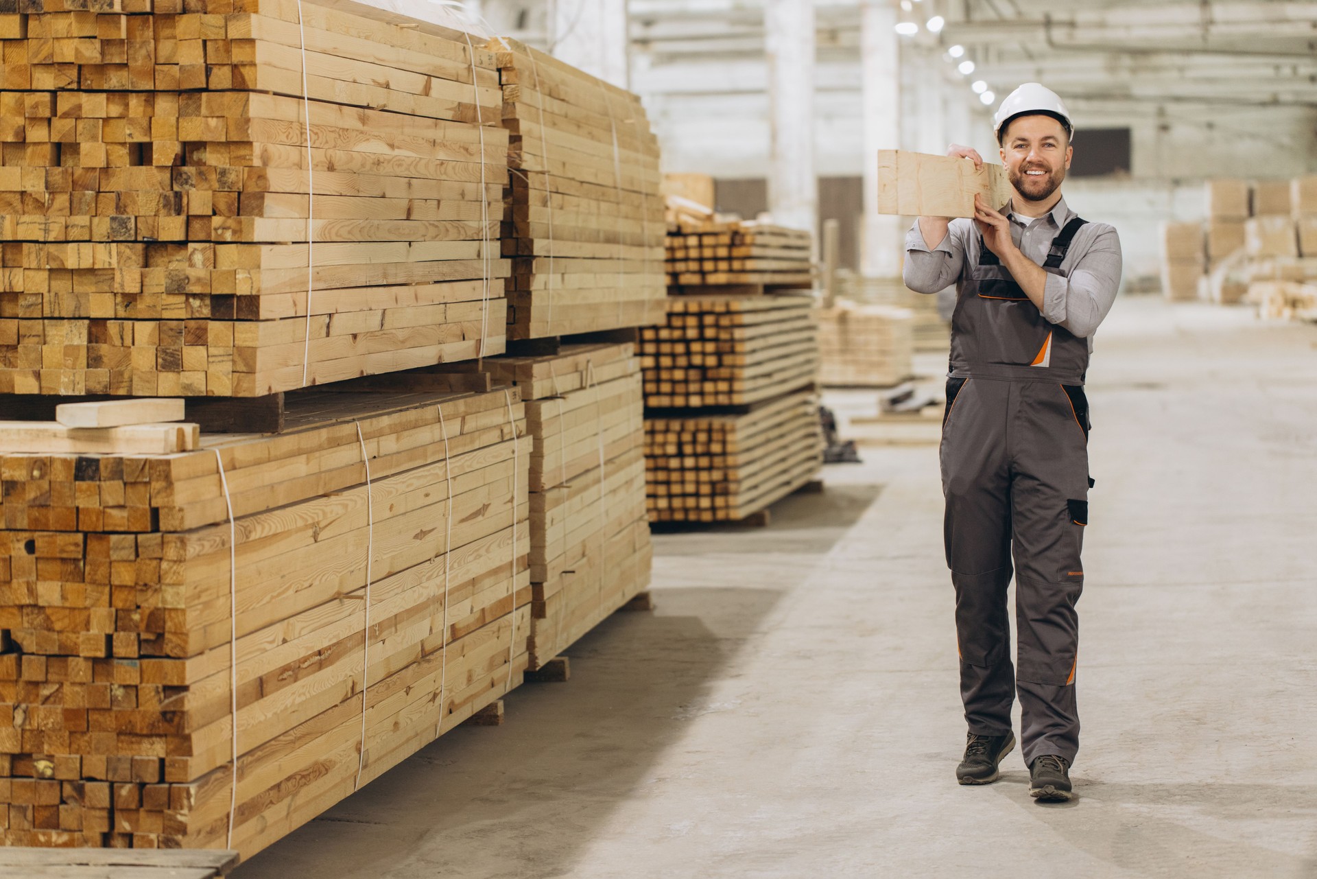 Carpenter holding wooden plank in timber warehouse for modular building